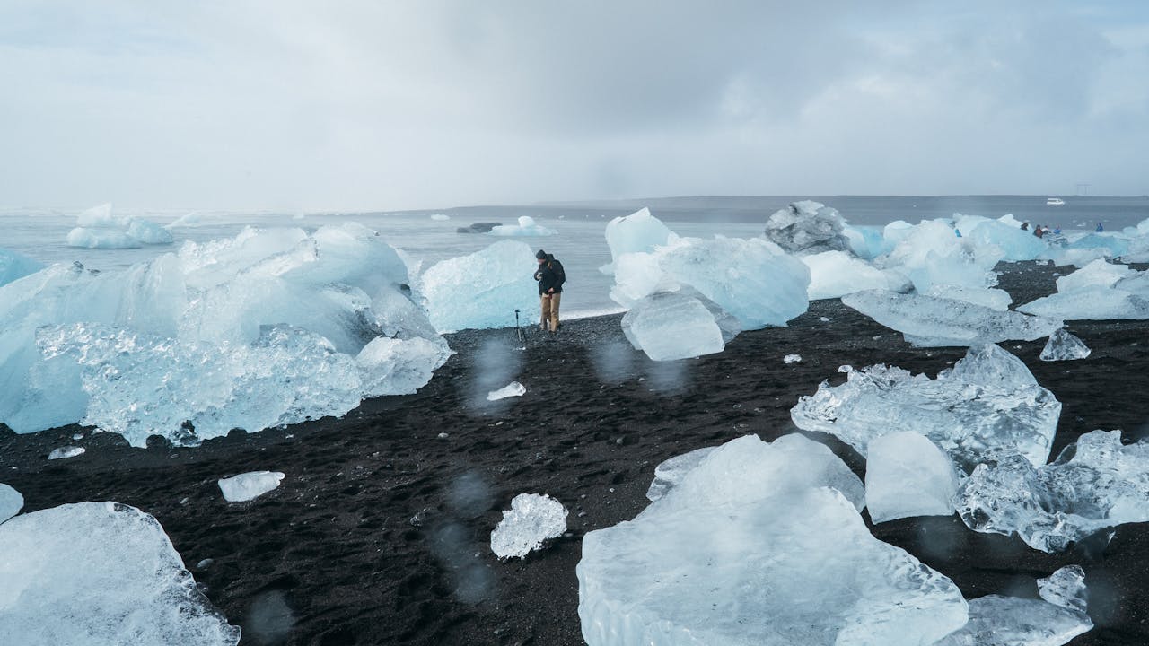 pexels-photo-1670845 Explore the breathtaking contrast of icebergs on a black sand beach with a solitary figure capturing the moment.